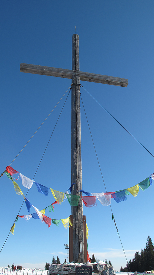 Multikultureller Fokus auf dem Schöckl, Gebetsfahnen schmücken das Gipfelkreuz. Foto: ©Auferbauer