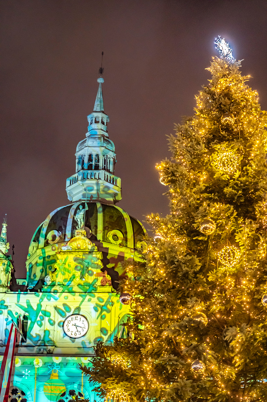 Der illuminierte Christbaum vor der weihnachtlichen Rathaus-Projektion.