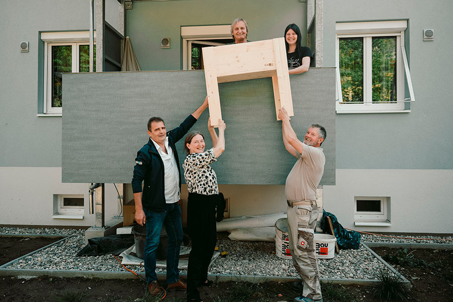 Über die neuen Balkone in der Triester Siedlung freuen sich nicht nur die Mieter:innen, sondern auch Bürgermeisterin Elke Kahr (stehend, Mitte). Zudem wurden die Balkone auf Wunsch kostenlos mit Hochbeeten ausgestattet. 