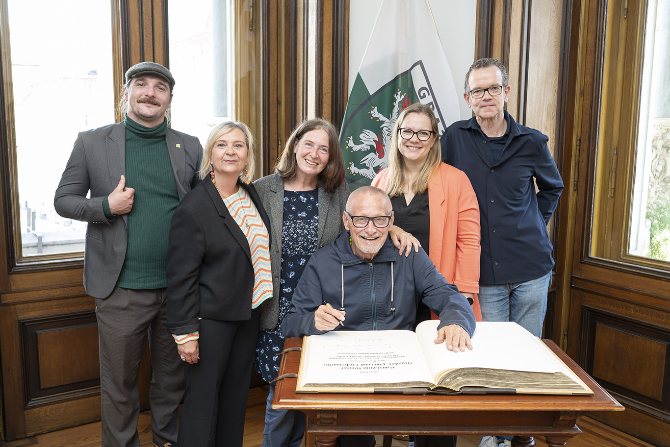 Konstantin Wecker trug sich in das Goldene Buch der Stadt Graz ein. Bild: Bgm.in Elke Kahr (M.), Pianist Jo Barnikel (r.), Claudia Klimt-Weithaler (KPÖ-Abgeordnete zum Steirischen Landtag), SPÖ-Klubvorsitzende Daniela Schüsselberger (2. v. r.) sowie Gemeinderat Tristan Ammerer (l.). © Stadt Graz/Fischer Konstantin Wecker trug sich in das Goldene Buch der Stadt Graz ein. Bild: Bgm.in Elke Kahr (M.), Pianist Jo Barnikel (r.), Claudia Klimt-Weithaler (KPÖ-Abgeordnete zum Steirischen Landtag), SPÖ-Klubvorsitzende Daniela Schüsselberger (2. v. r.) sowie Gemeinderat Tristan Ammerer (l.).