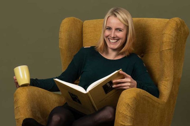 Frau mit einem Buch in der Hand auf einem Lehnsessel