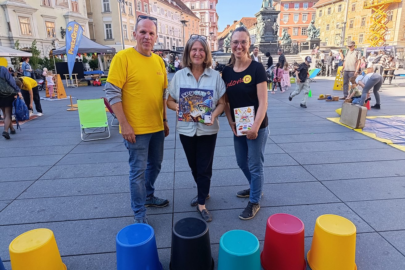 Bürgermeisterin Elke Kahr (Mitte) zu Besuch beim großen Spielfest am Hauptplatz - mit Ernst Muhr (GF Fratz Graz) und Sarah Ulrych (GF Ludovico).